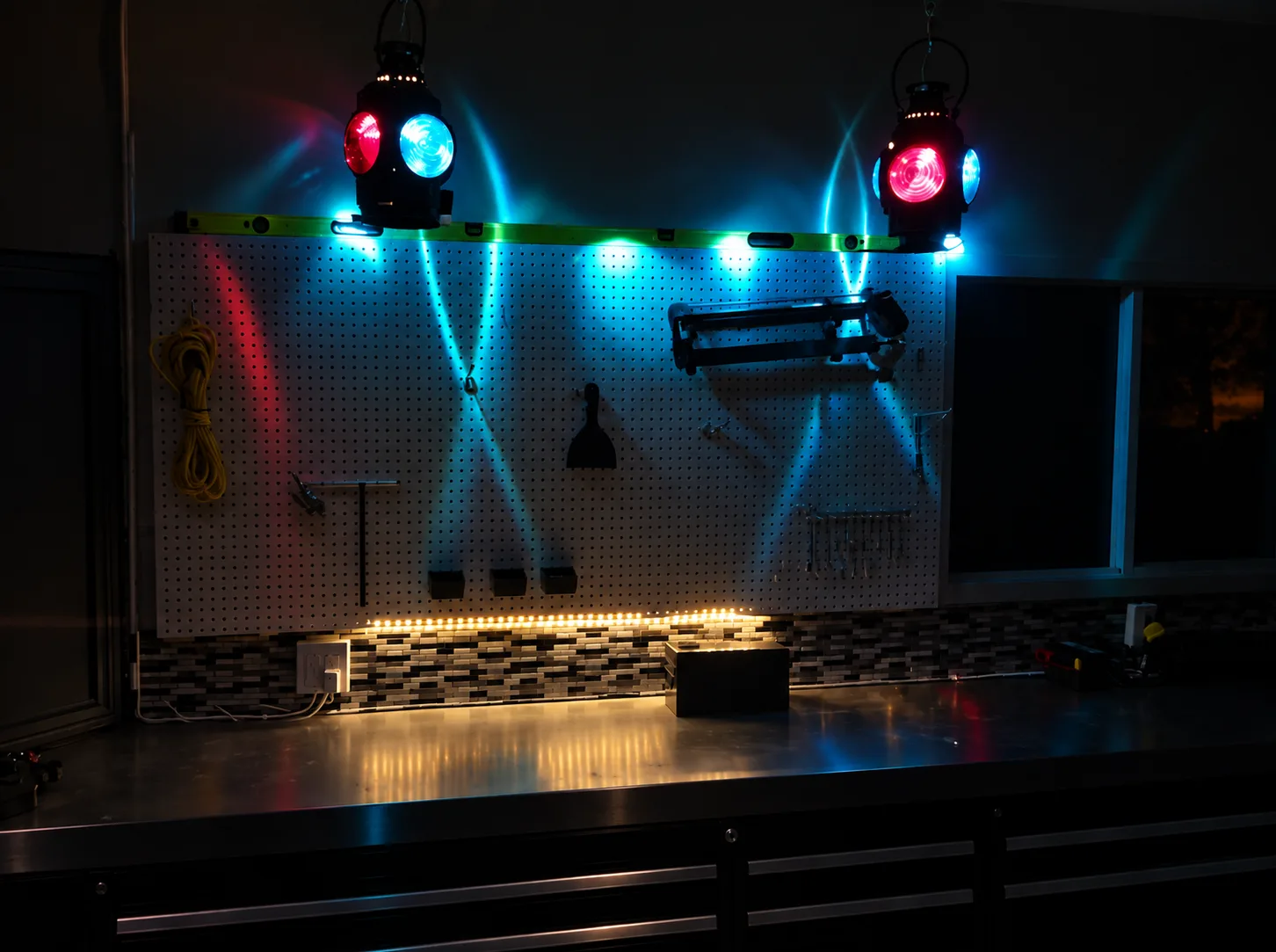 Workshop workbench setup with a pegboard wall, glowing blue and red lantern lights, LED strip lighting, and hanging tools.